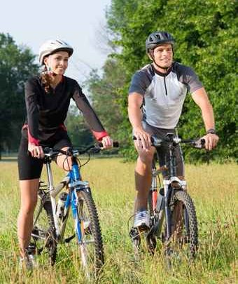 Young Couple With Bicycle In Meadow